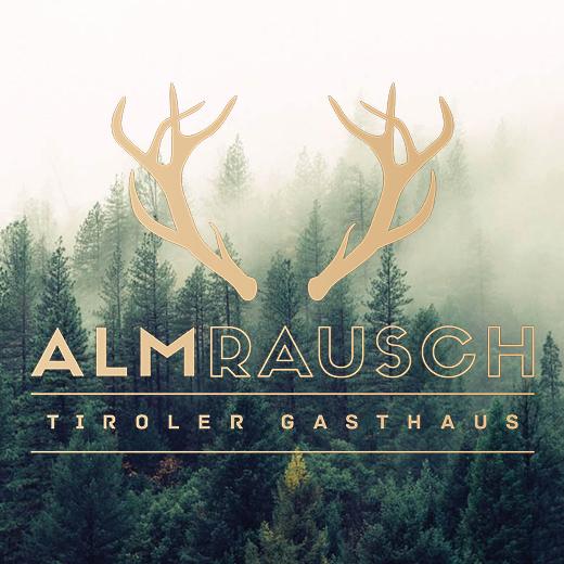 Almrausch – Tiroler Gasthaus Dresden | Logo Logo des Almrausch – Tiroler Gasthaus in Dresden mit goldenen Hirschgeweihen vor einem Waldmotiv.